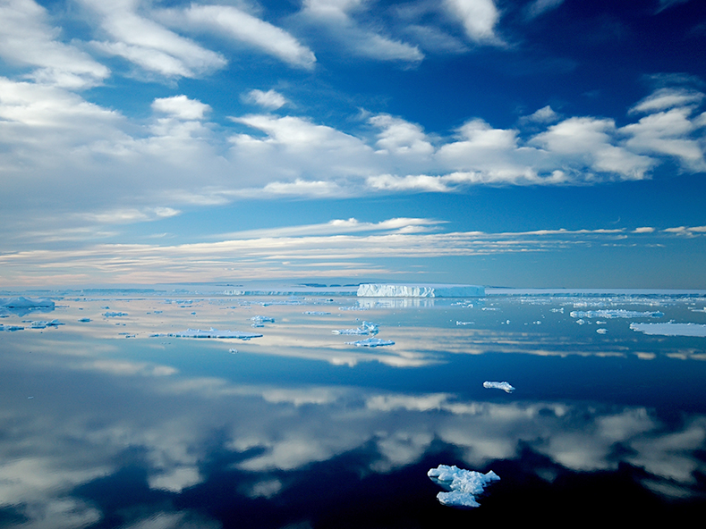 Antarctic iceberg and cloud landscape reflecting calm waters near Ross Island