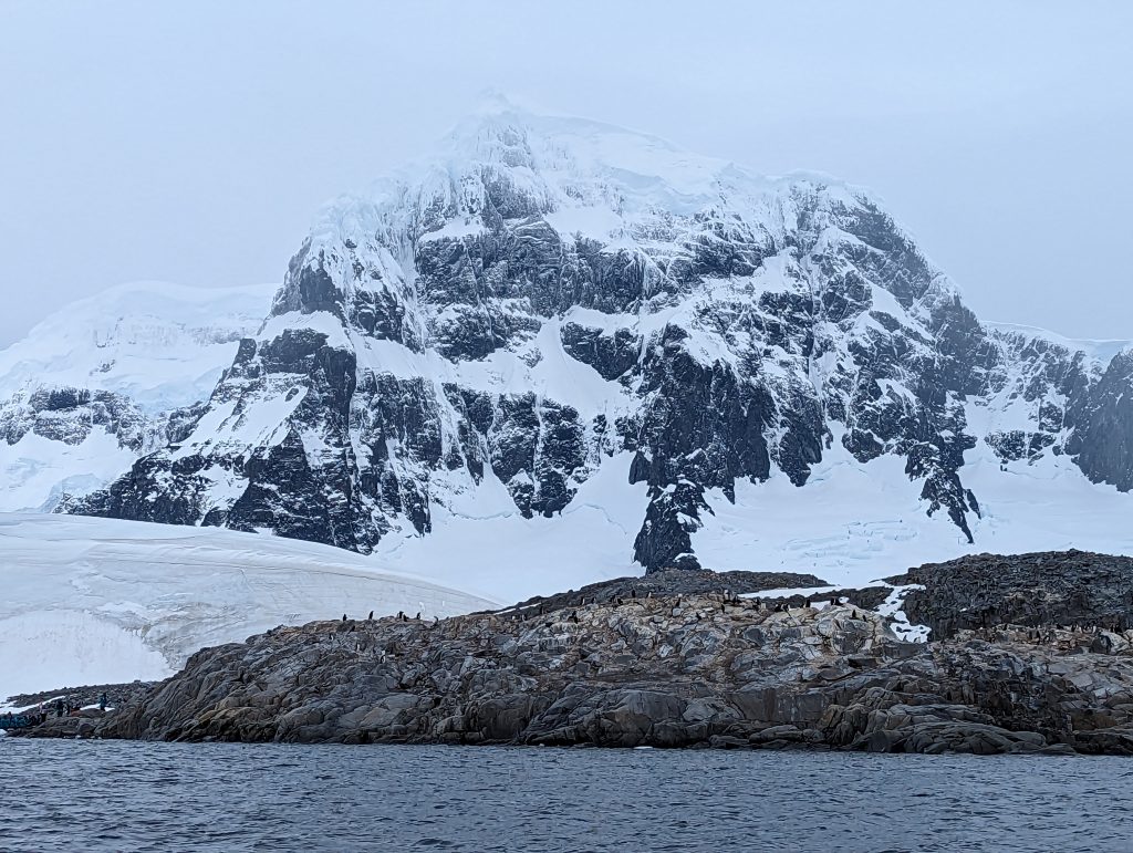 A frozen mountain backdrops an Antarctic penguin colony